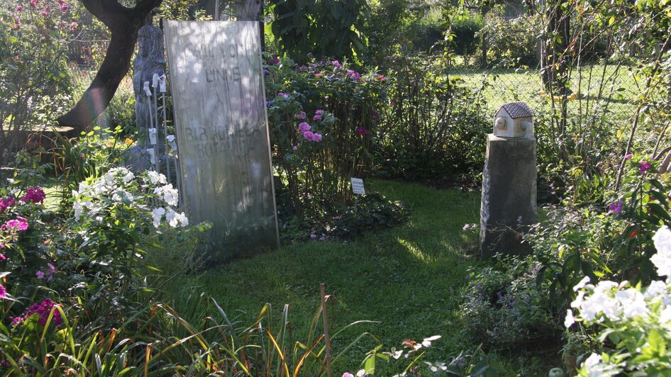 Ein Garten mit Grabsteinen und bunten Blumen. | © kunstGarten