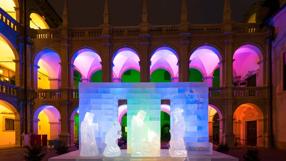 Eiskunstwerk einer Krippe im Landhaushof, beleuchtet von bunten Lichtern. | © Graz Tourismus - Harry Schiffer