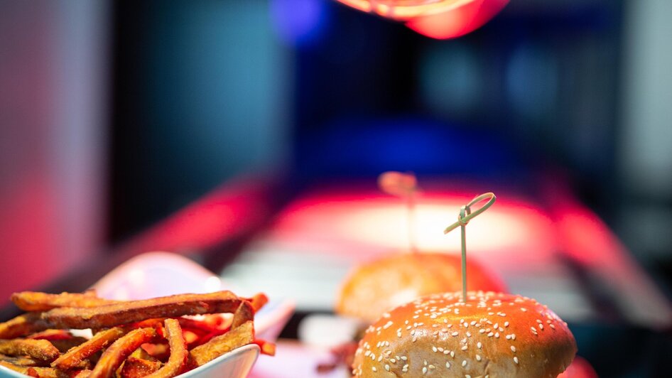 Ein Burger mit Pommes, beleuchtet unter einer Wärmelampe. | © The Guardians