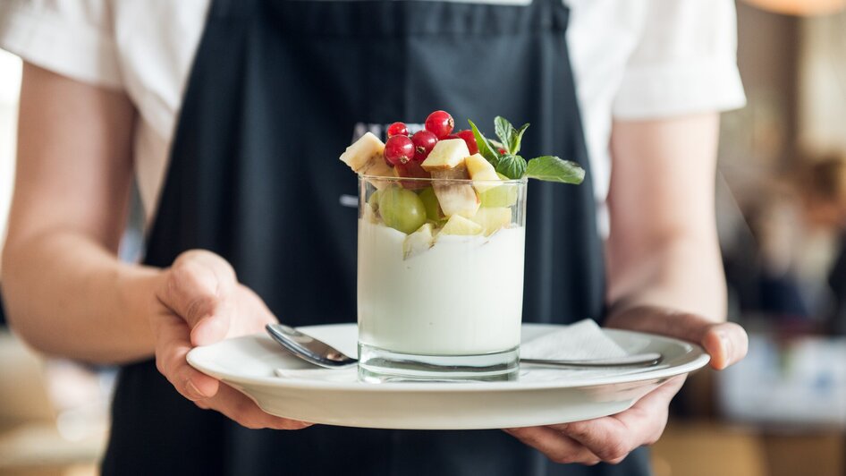 Ein Dessert mit Joghurt und frischem Obst, serviert in einem Glas.
