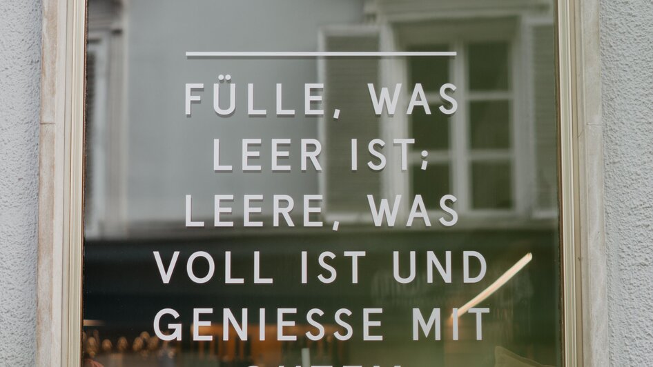 Fensterscheibe mit dem Spruch: "Fülle, was leer ist. Leere, was voll ist und genieße mit gutem Gewissen."