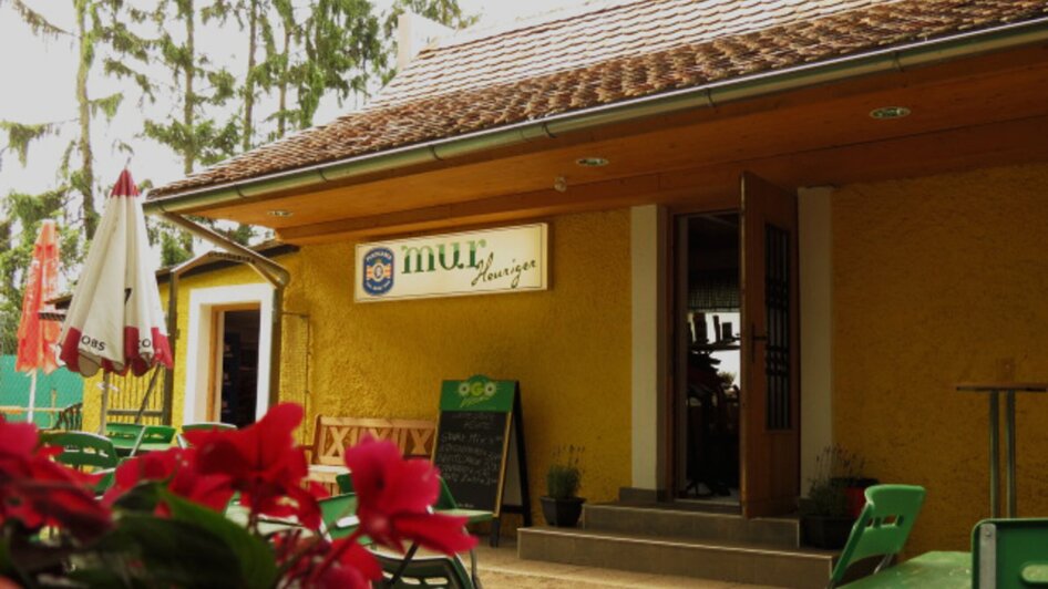 Gemütliches Lokal mit gelber Fassade und Außenbereich, ideal für Essen und Trinken.