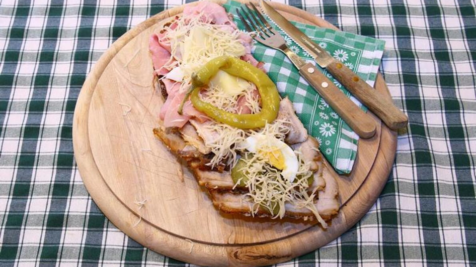 Ein Holzbrett mit einem Schinkenbrot mit Kren und Ei.