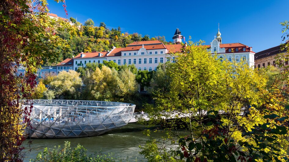 Die Murinsel in Graz vor malerischer Kulisse.