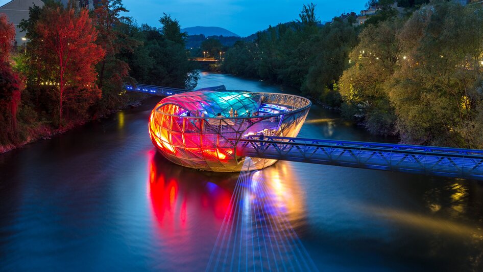 Die Murinsel in Graz leuchtet farbenfroh über der Mur.