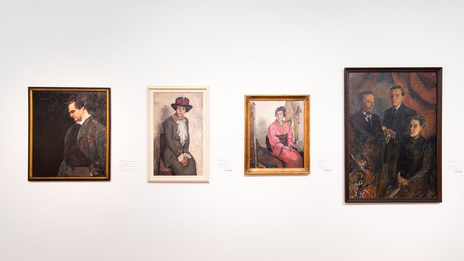 Verschiedene Porträts in einer Galerie mit neutralem Hintergrund.