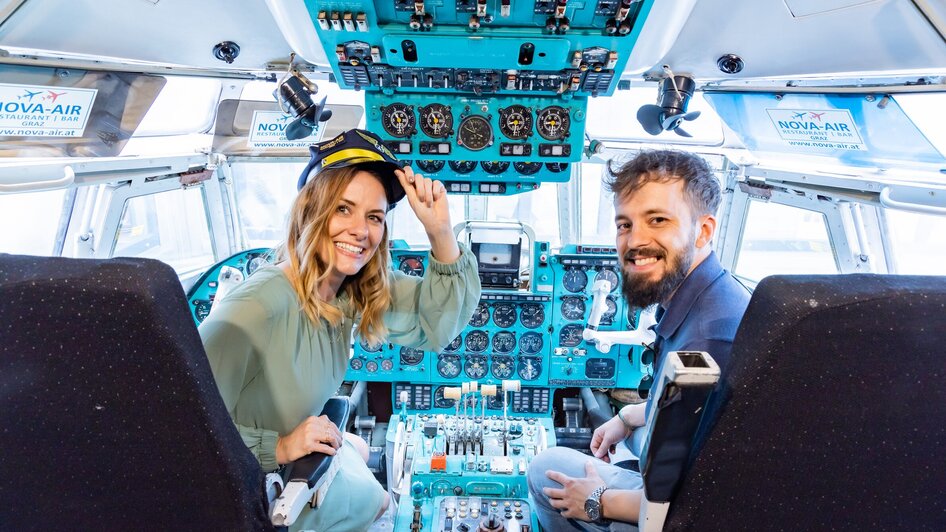Zwei Personen im Cockpit eines Flugzeugs im Novapark Flugzeughotel Graz.