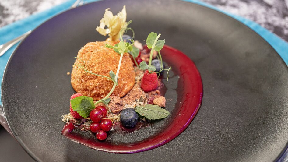 Ein feines Dessert mit Beeren und Sauce, präsentiert auf einem eleganten Teller.