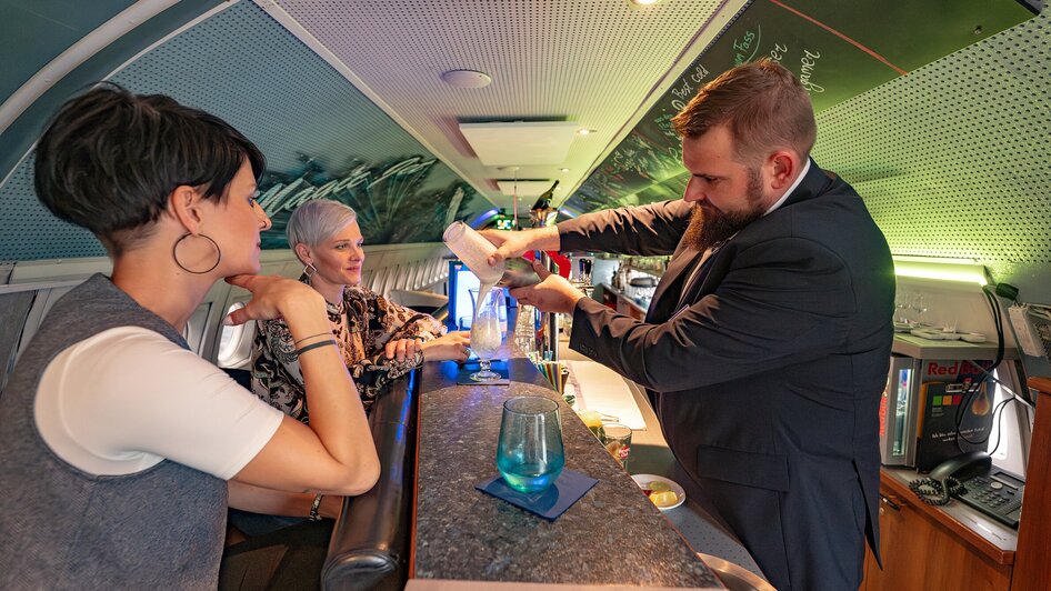 NOVA-AIR in Graz: Barkeeper mixt Drink für Gäste in stylisierter Atmosphäre.