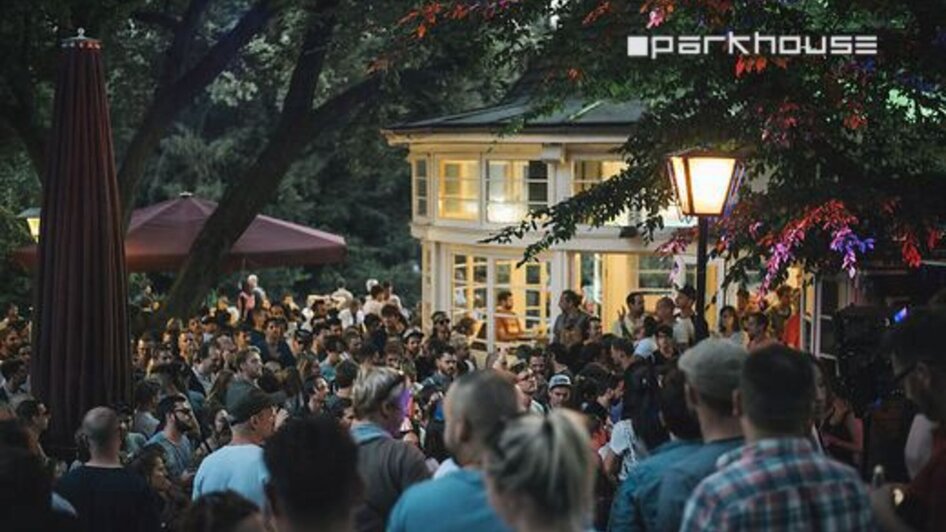 Menschenmenge im Parkhouse, bei Abendstimmung im Stadtpark Graz.