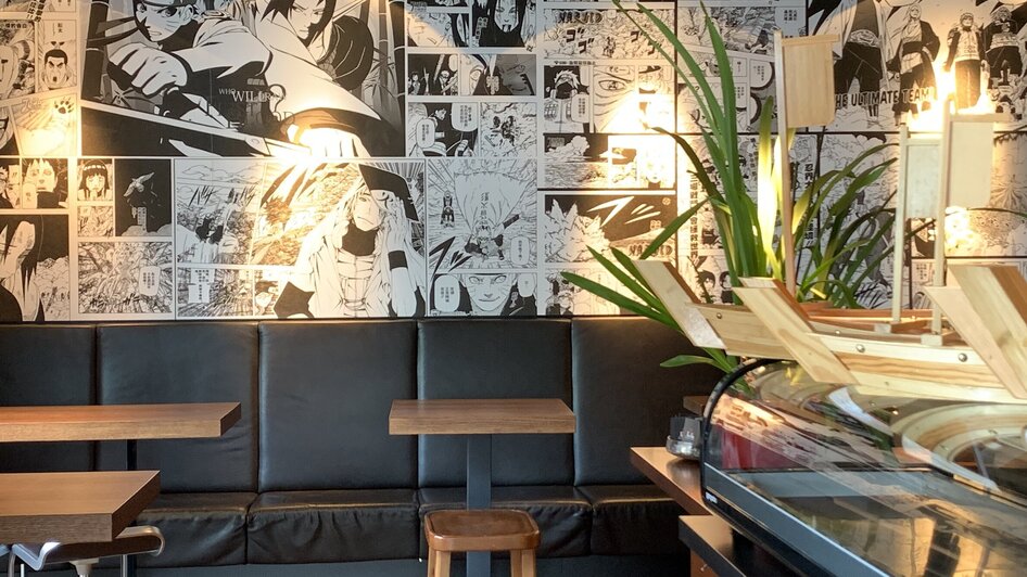 Gemütlicher Restaurantbereich mit Manga-Wanddekoration.