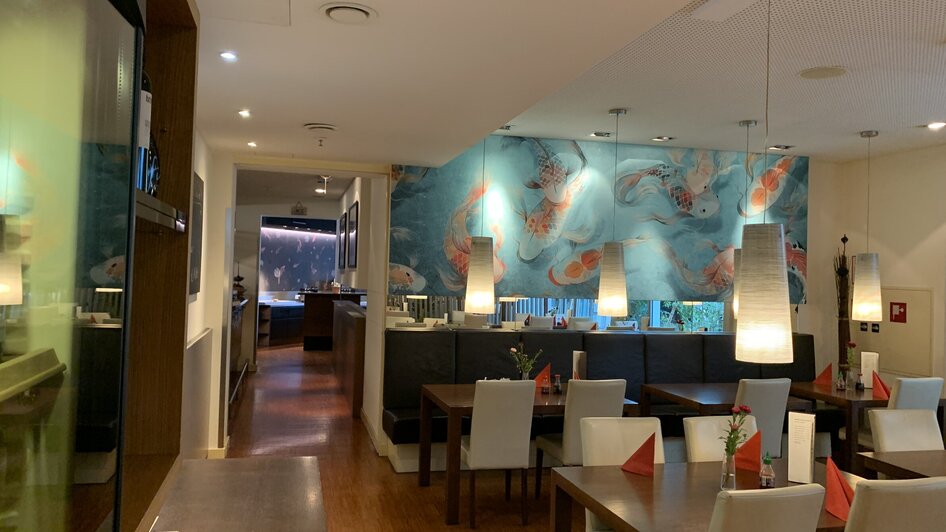 Gemütliches Restaurant mit asiatischer Einrichtung und Wandmalerei.