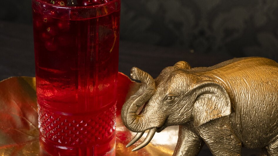 Pink Elephant I Essen & Trinken in Graz | © Jauk Katharina Ein goldener Elefant neben einem Glas mit rotem Getränk und Beeren. | © Jauk Katharina