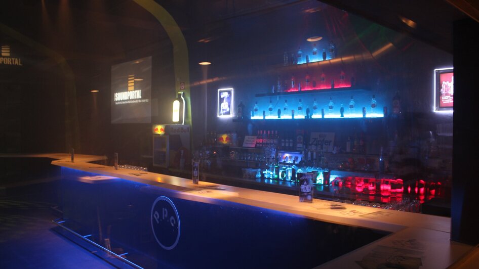Beleuchtete Bar mit Getränken und moderner Atmosphäre.