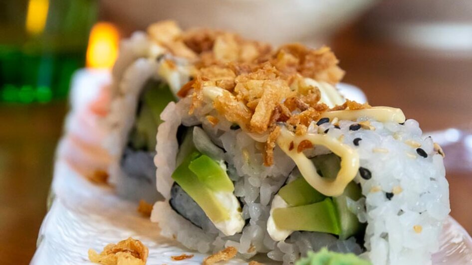 Leckeres Sushi mit Avocado, Sesam und Zwiebelchips.