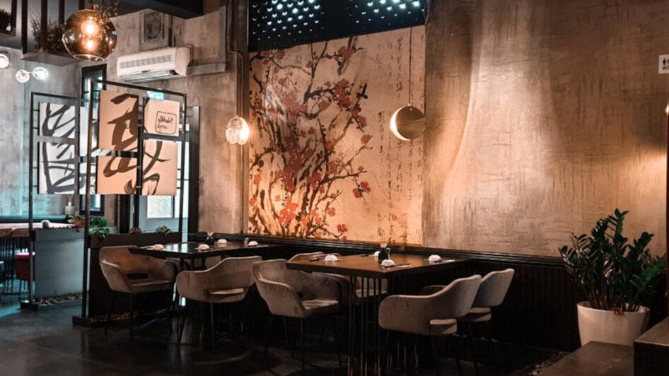 Stilvolles Asia Restaurant Sakana mit gemusterter Wand und modernen Möbeln.