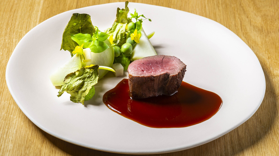 Saftiges Fleisch mit Beilagen auf elegantem Teller.