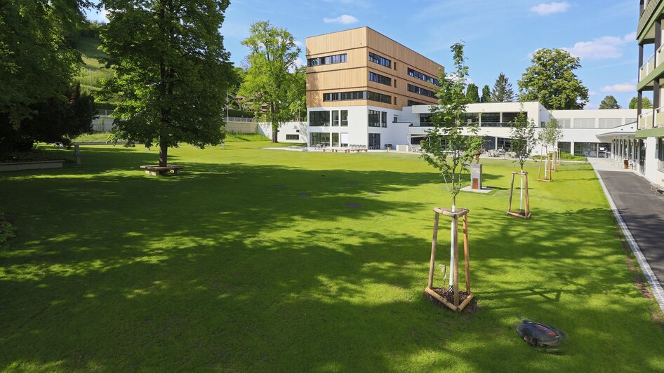 Außenansicht des Steiermarkhofs umgeben von Grünflächen und Bäumen.