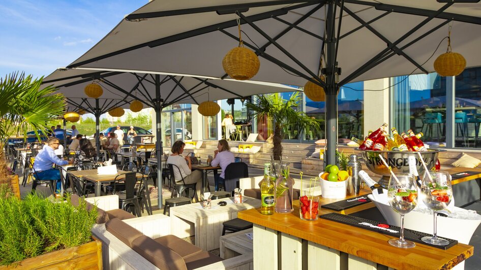 Gemütlicher Restaurantbereich im Freien mit Cocktails und Gästen.