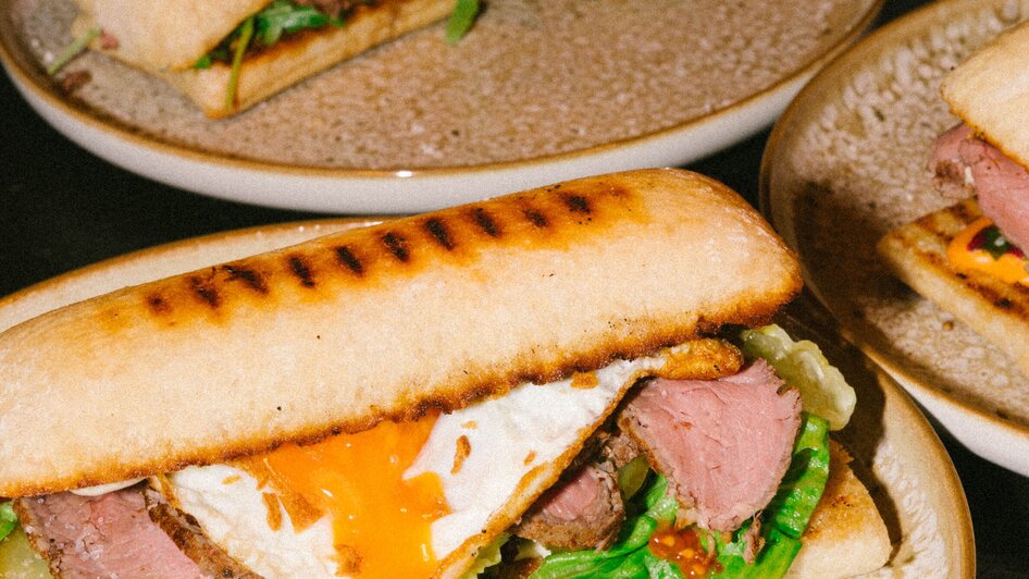 Ein gegrilltes Sandwich mit Rindfleisch, Spiegelei und frischem Gemüse. | © Bobby's Agency - Simon Bauer