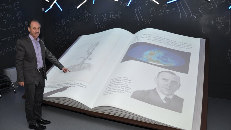 Eine Person zeigt auf ein großes, offenes Buch im Museum. | © UniGraz@Museum