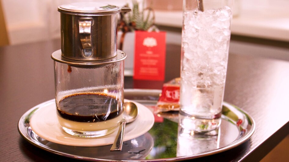 Ein Glas Kaffee in einem Restaurant mit einem Glas Wasser mit Eiswürfel.