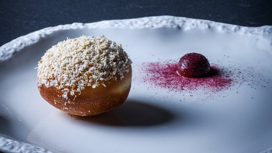 Ein kunstvoll angerichtetes Dessert auf einem weißen Teller.