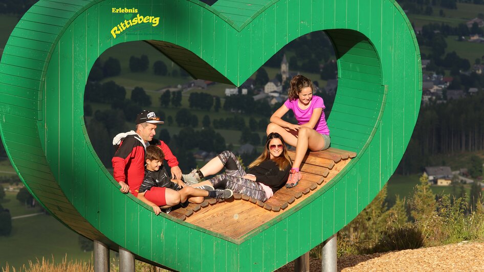 Das grüne Herz am Rittisberg | © Erlebnis Rittisberg Familie sitzt in der Mitte des grünen Herzens. | © Erlebnis Rittisberg