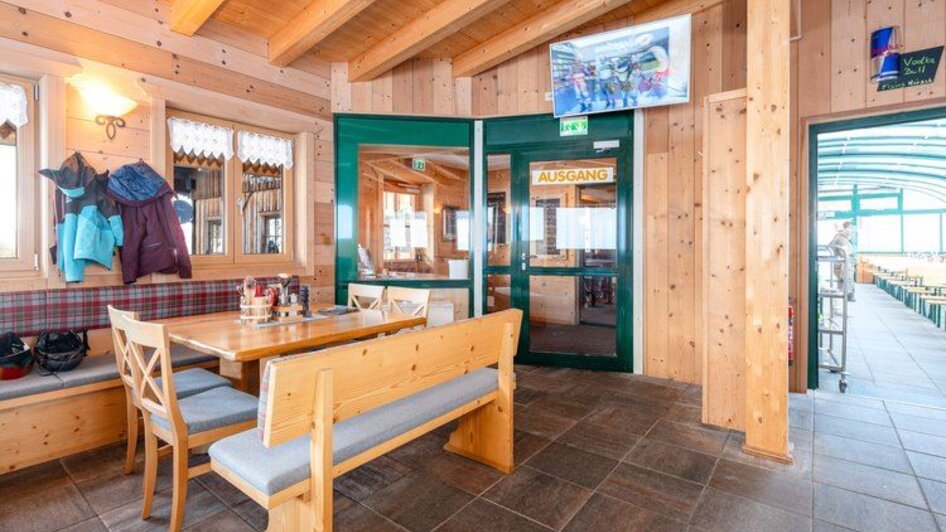 Gemütlicher Gastraum mit Holzwänden, Polsterbänken und Holztischen, warm beleuchtet. | © Mitterhausalm | Alpine Genusswelten